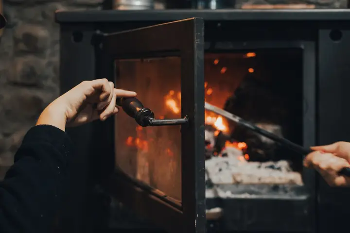 Main ouvrant la porte vitrée d’un insert allumé